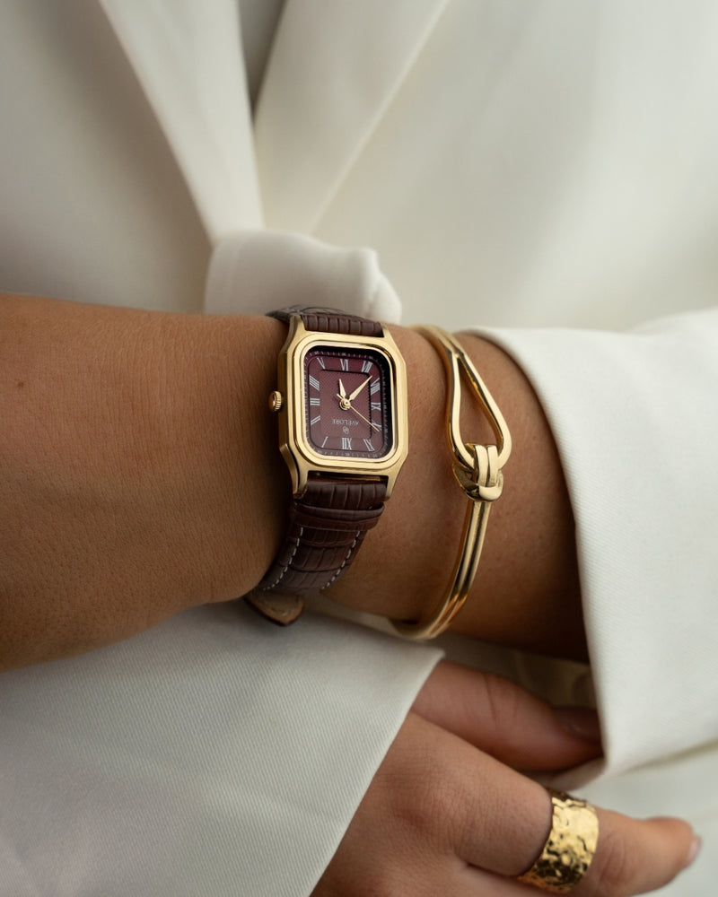 A gold bracelet with loop knot detail. The model is Coce Bangle by Avelore Women's Bracelets.