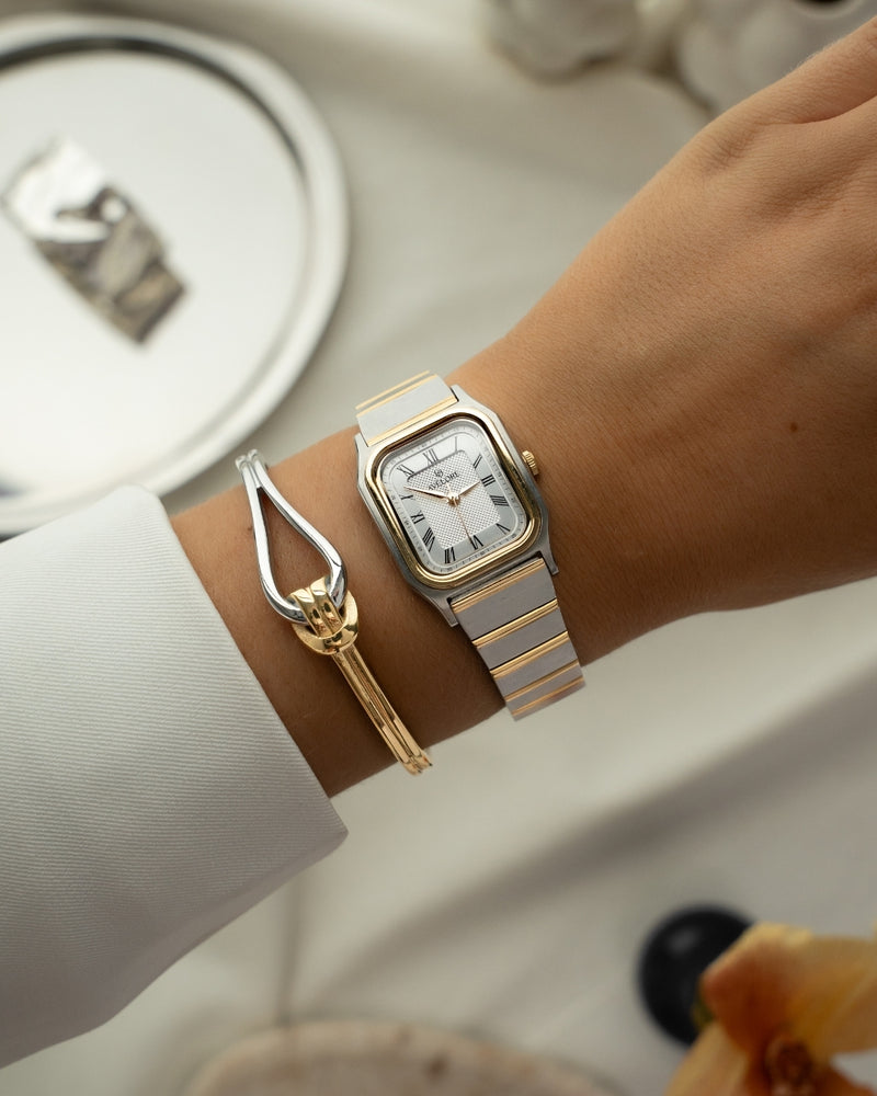Two-tone square watch for women with silver dial and silver and gold band. The model is Aima by Avelore.
