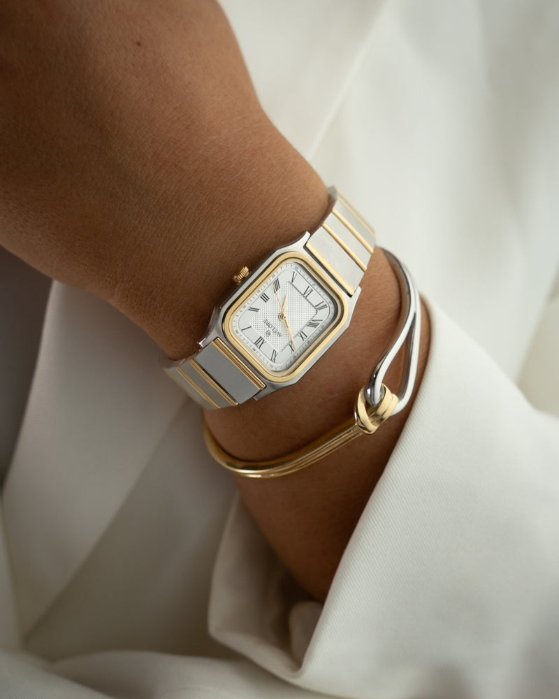 A gold and silver bracelet with loop knot detail. The model is Coce Bangle by Avelore Women's Bracelets.
