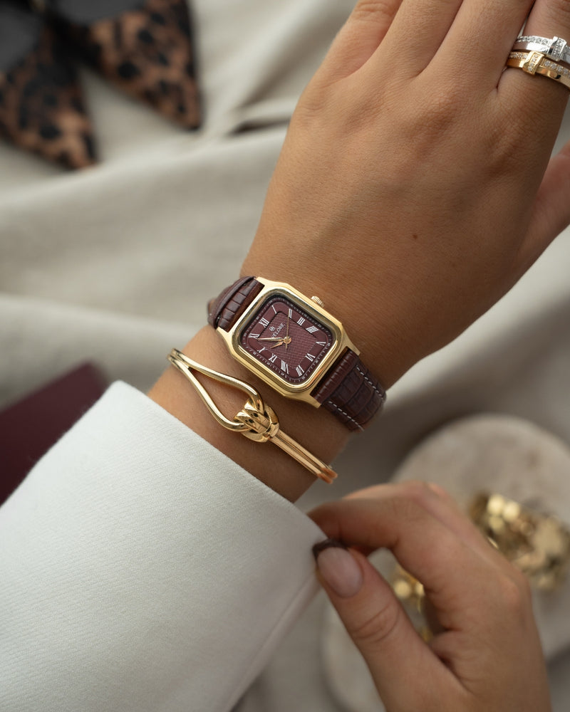 Gold square watch for women with burgundy dial and burgundy leather band. The model is Aima by Avelore.