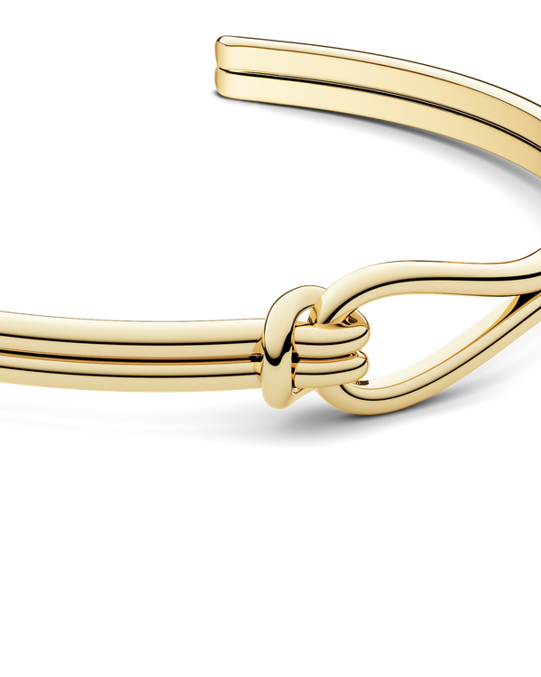 A gold bracelet with loop knot detail. The model is Coce Bangle by Avelore Women's Bracelets.