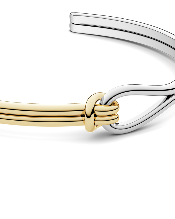 A gold and silver bracelet with loop knot detail. The model is Coce Bangle by Avelore Women's Bracelets.