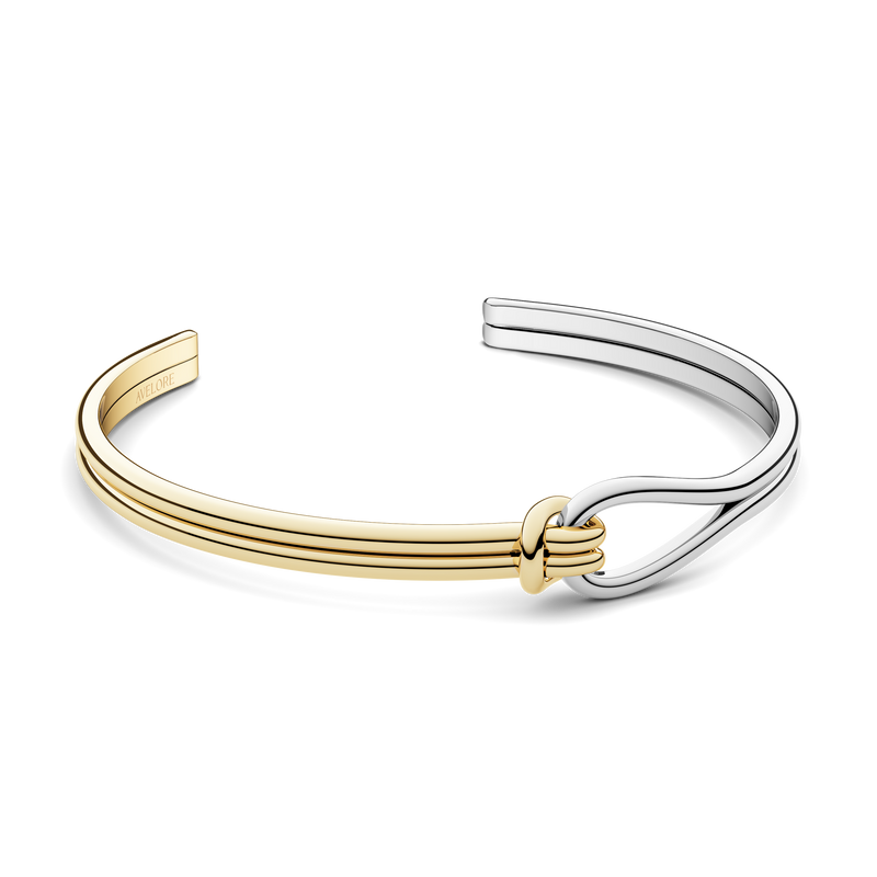 A gold and silver bracelet with loop knot detail. The model is Coce Bangle by Avelore Women's Bracelets.