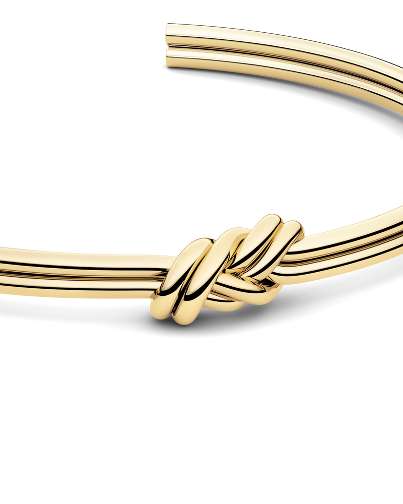 Gold bracelet with triple knot detail. The model is Naia bangle by Avelore Women's Bracelets