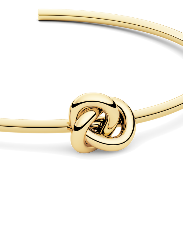 Gold bracelet with a knot design. The model is Veda Bangle by Avelore. Women's Bracelets