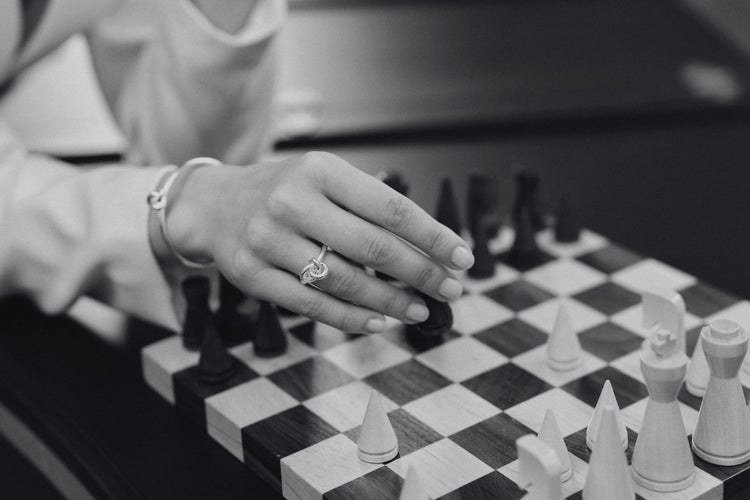 Woman playing chess with a close-up of her silver Veda ring and bracelet from Avelore.