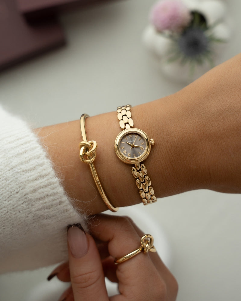Gold round small watch for women with brown dial and gold band. The model is Eira by Avelore.
