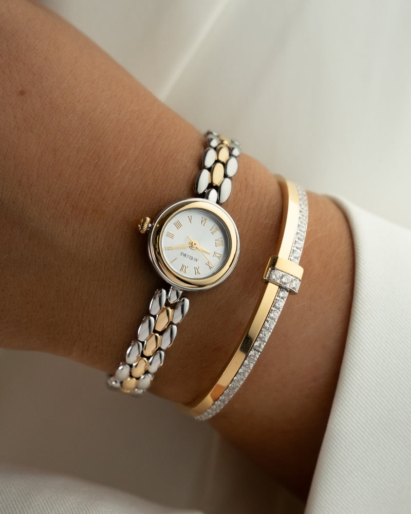 Two-tone round small watch for women with silver dial and silver and gold band. The model is Eira by Avelore.