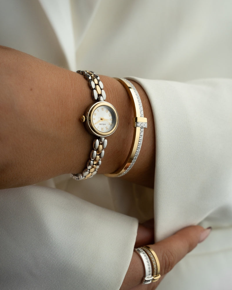 Two-tone round small watch for women with silver dial and silver and gold band. The model is Eira by Avelore.