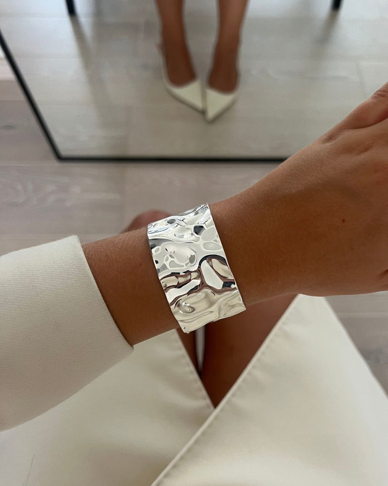 Wide silver cuff bracelet with hammered patterned surface. The model is Noem Bangle by Avelore  Women's Bracelets