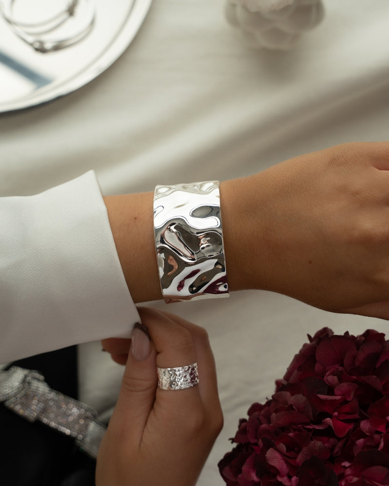 Wide silver cuff bracelet with hammered patterned surface. The model is Noem Bangle by Avelore  Women's Bracelets