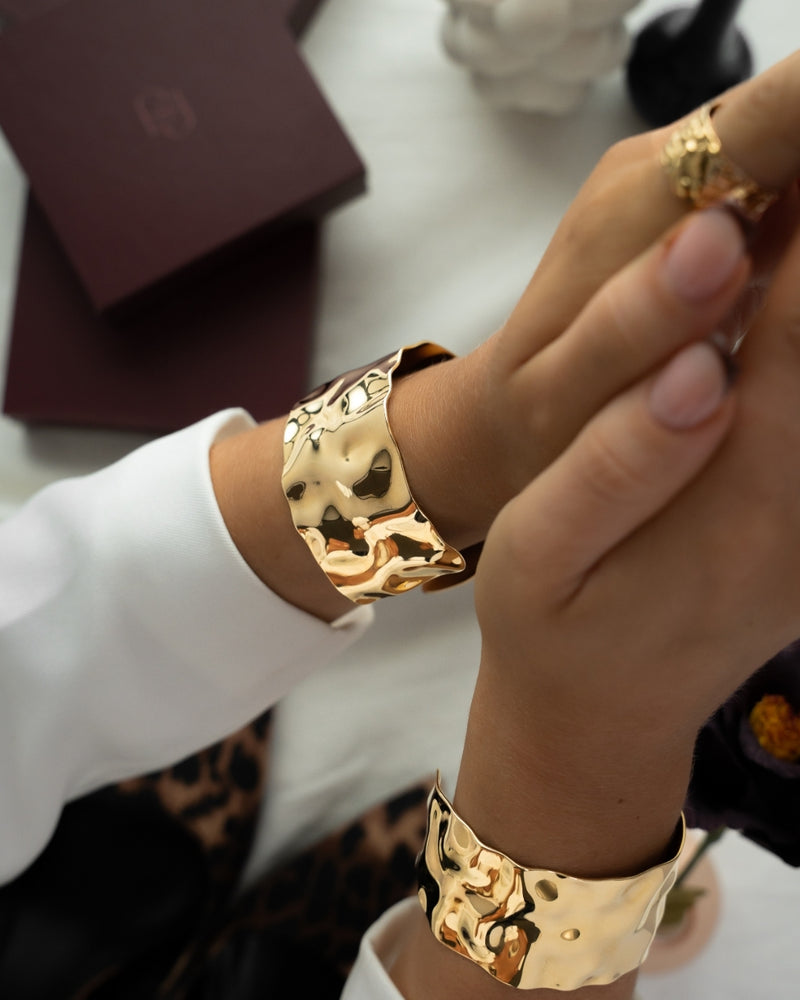 Wide gold cuff bracelet with hammered patterned surface. The model is Noem Bangle by Avelore  Women's Bracelets