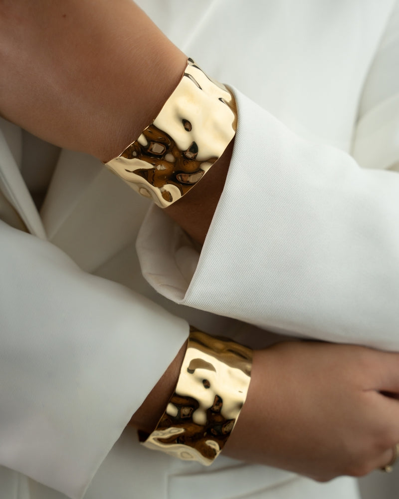 Wide gold cuff bracelet with hammered patterned surface. The model is Noem Bangle by Avelore  Women's Bracelets