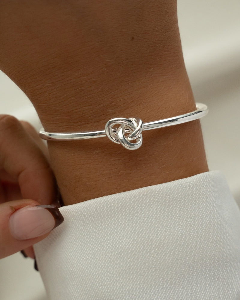 Silver bracelet with a knot design. The model is Veda Bangle by Avelore. Women's Bracelets