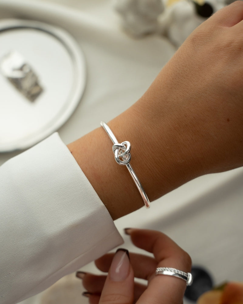 Silver bracelet with a knot design. The model is Veda Bangle by Avelore. Women's Bracelets